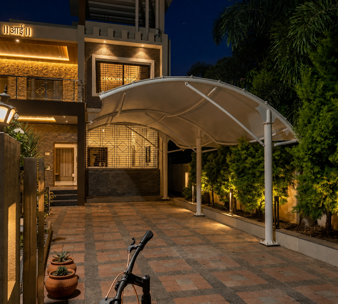 Illuminated cantilever tensile canopy over a residential driveway at night