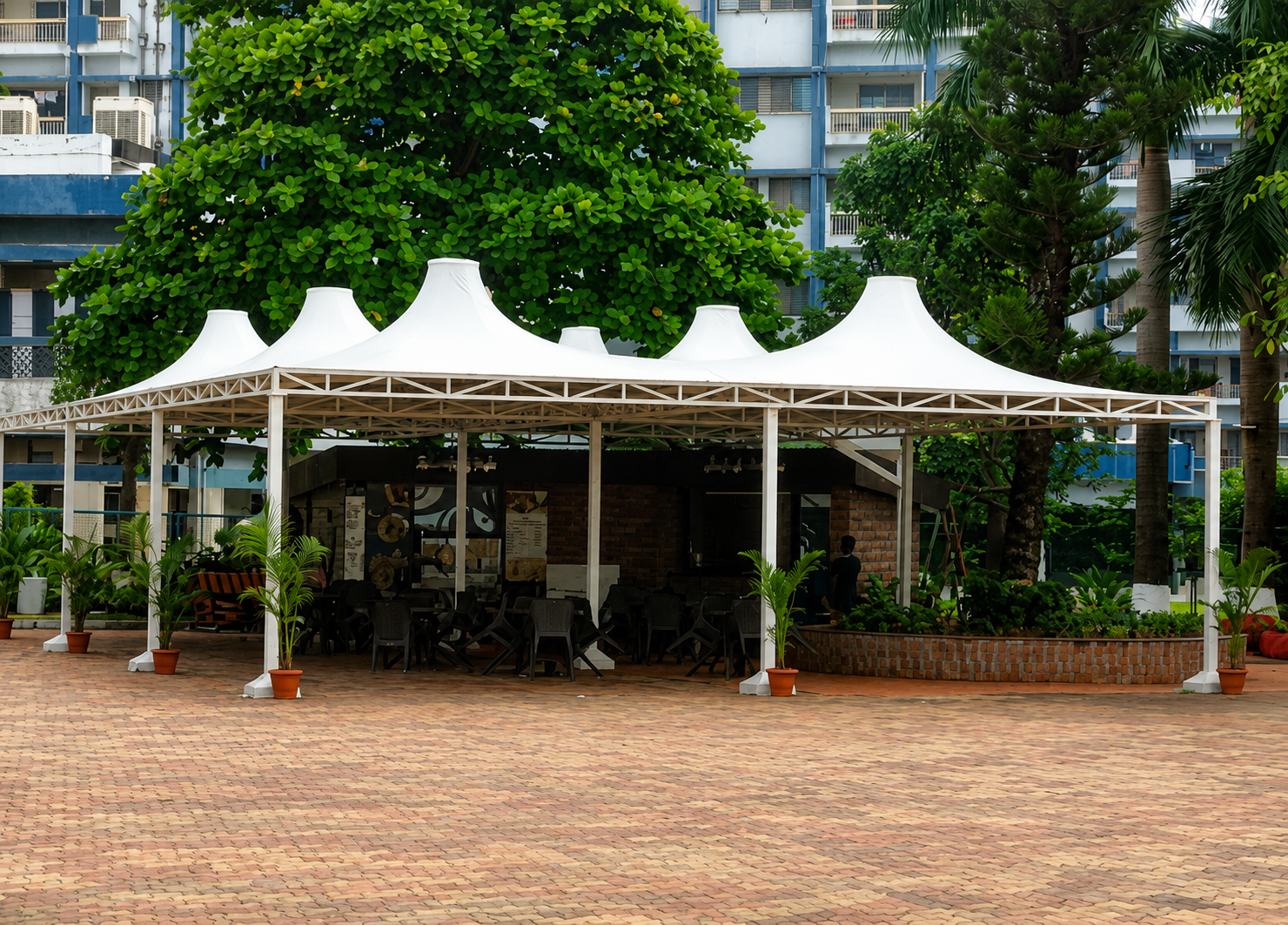 Conical multi-peak tensile gazebo over an outdoor seating area